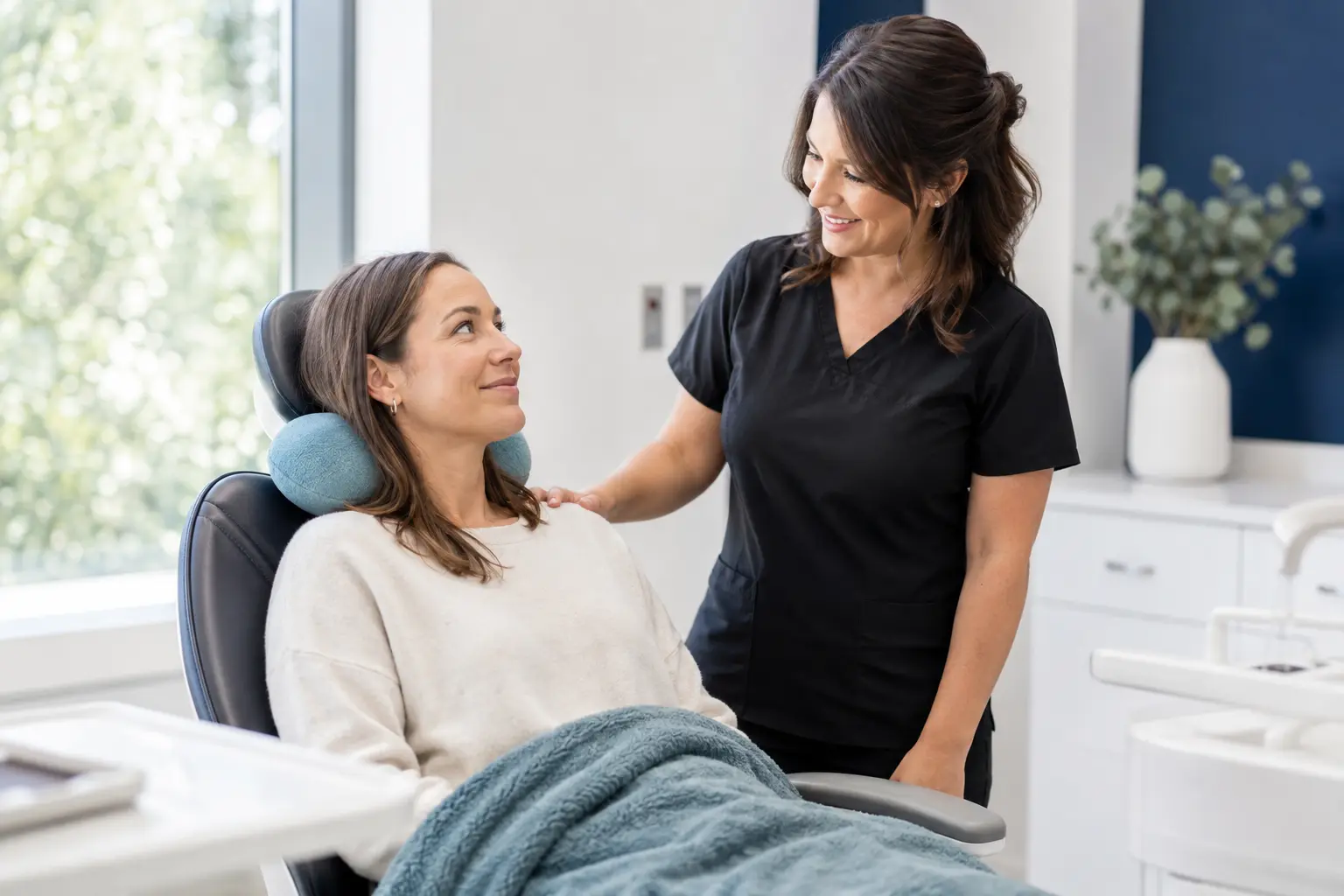 A dental team member helping a patient feel comfortable with a blanket and neck pillow